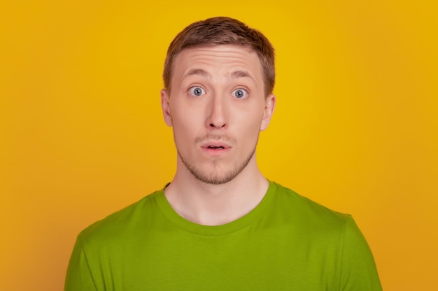 Photo of young man amazed shocked surprised fake novelty news reaction isolated over yellow color background