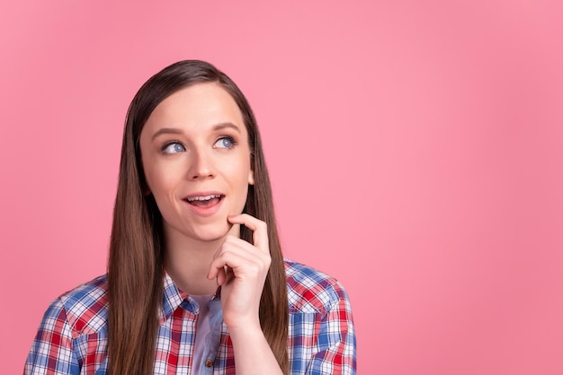 Photo of young pretty girl finger touch chin curious wondered look empty space isolated over pink color background