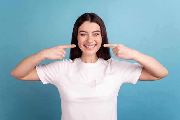 Photo of young pretty girl indicate fingers teeth hygiene cavity protection isolated over blue color background.