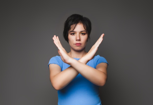 A photo of a young pretty serious woman with her arms crossed shows the forbidden no stop symbol highlighted against a gray background