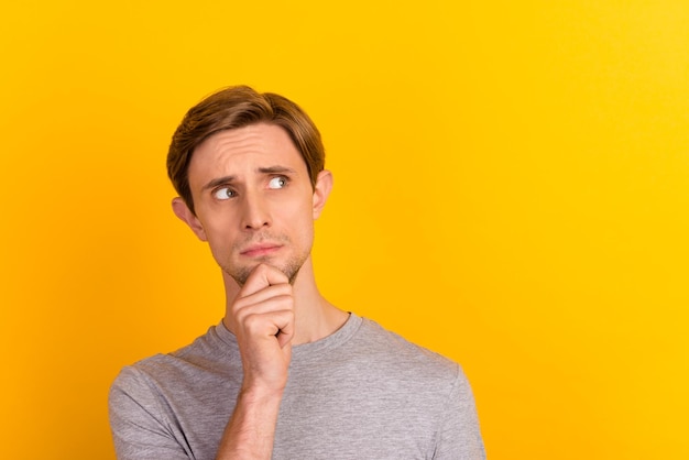 Photo of young uncertain guy hand touch chin think look empty space isolated over pastel color background