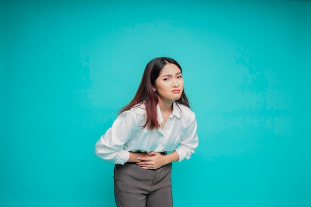 Photo photo of young unwell sick ill woman hold hand on stomach suffers pain isolated on blue background