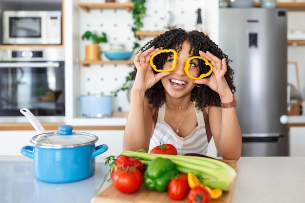 Photo of young woman smiling while cooking salad with fresh vegetables in kitchen interior at home