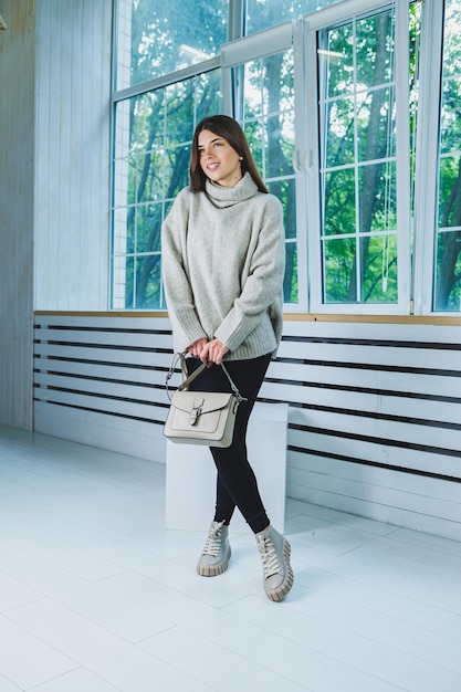 Photo of a young woman in white boots and casual clothes New collection of women's winter shoes made of genuine leather