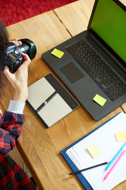 Photographer female working in a creative office holding camera at desk and retouch photo