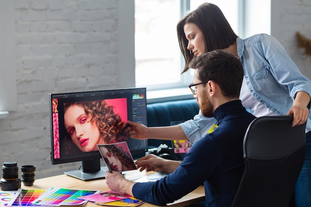 Photographer and graphic designer working in office with laptop, monitor, graphic drawing tablet and color palette.