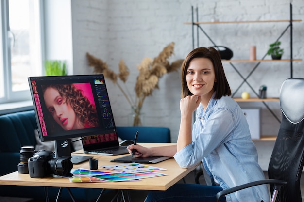 Photographer and graphic designer working in office with laptop, monitor, graphic drawing tablet and color palette.