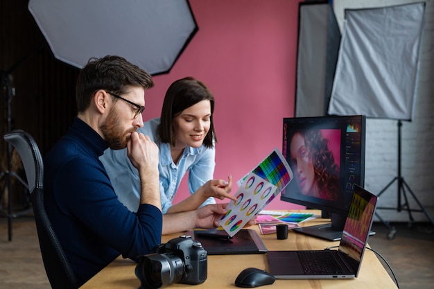 Photographer and graphic designer working in office with laptop, monitor, graphic drawing tablet and color palette.