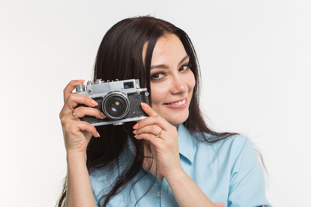 Photographer, hobby and people concept - Young brunette woman with retro camera on white background.