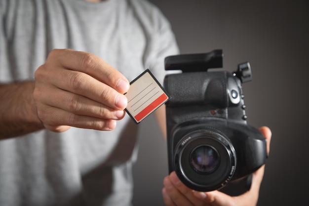 Photographer holding memory card insert DSLR camera