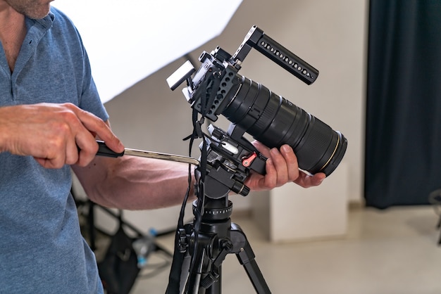 A photographer man tuns up a professional camera for work on the studio