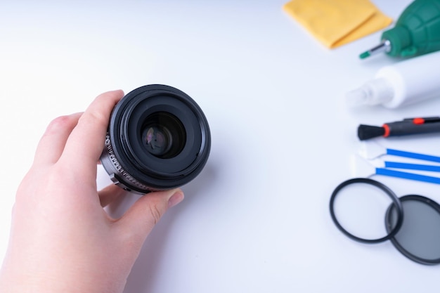 Photo photographer's hand holding a camera lens, accessories for cleaning the camera on a white background