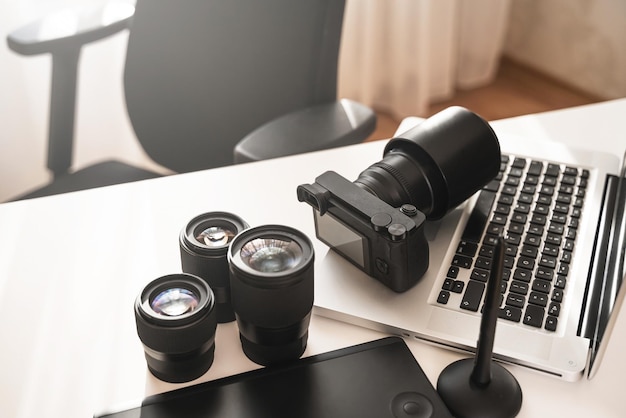 Photographer's workplace with a modern equipment. Mirrorless camera, laptop and prime lenses.