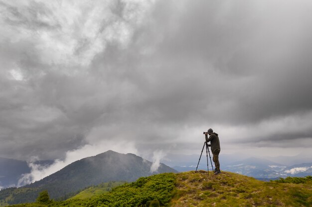 The photographer standing on the mountain with rainy clouds