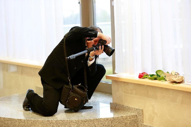 The photographer takes a photo A man with a camera photographs a flower