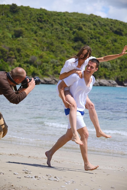 photographer taking photo of models couple on beautiful tropical beach at summer