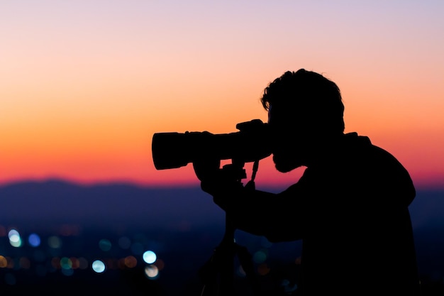 Photographer taking photo with DSLR camera at sunset