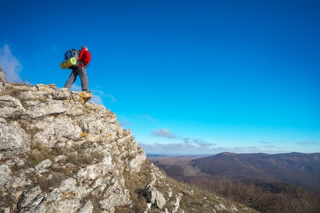 Photographer on top of the mountain in autumn. Traveler with backpack enjoying a view from the mountain top