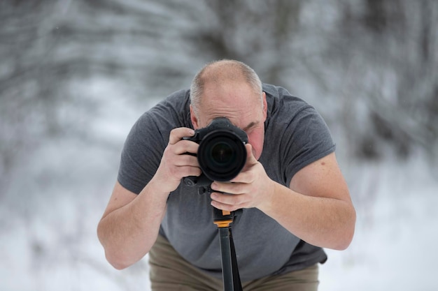 Photographer with a camera in the winter forest Elderly male photographer