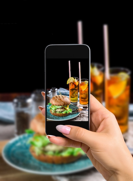 Photographing food concept  woman takes picture of sandwich with chicken burger cheese and lettuce