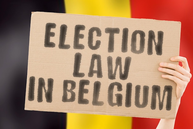 The phrase Election law in Belgium on a banner in men's hands with a blurred Belgian flag in the background Constitution Political Senate Brussels Electorate Majority