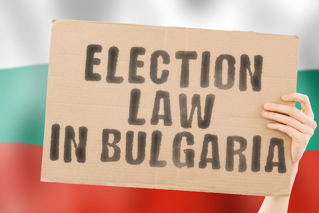 The phrase Election law in Bulgaria on a banner in men's hands with a blurred Bulgarian flag in the background Constitution Political Senate Sofia Electorate Majority