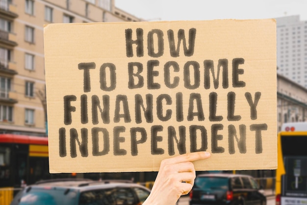 The phrase How to Become Financially Independent on a banner in men's hand with blurred background Dream Leader Career Bank Grow Growth Future Earn Cash Idea Plan Desire Advice Save