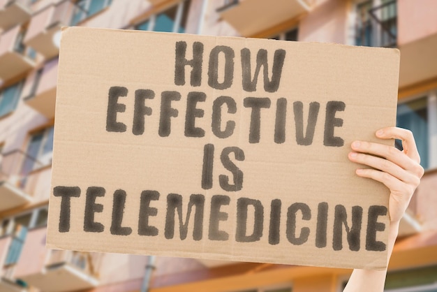 The phrase How effective is telemedicine is on a banner in men's hands with blurred background Trust Work Therapy Pharmacy Surgeon Disorder Disease Discovery Cyberspace Effective