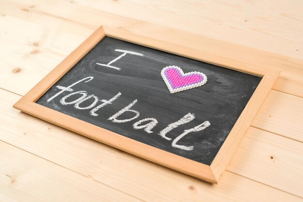 The phrase I LOVE FOOTBALL on a chalkboard, selective focus