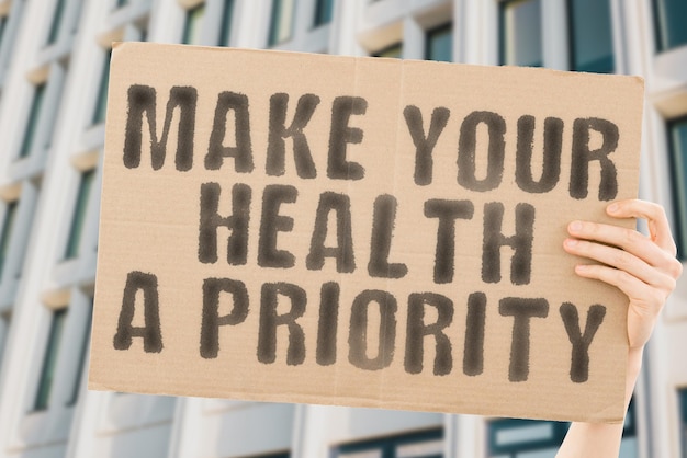 The phrase Make your health a priority is on a banner in men's hands with blurred background Motivate Psychological Sick Wealth Mental Health Healthiness Wellbeing Vitality Welfare