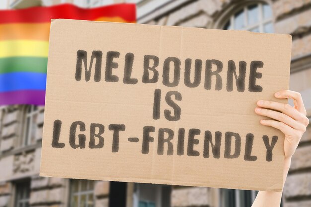 The phrase  Melbourne is LGBTFriendly  on a banner in mens hand with blurred LGBT flag