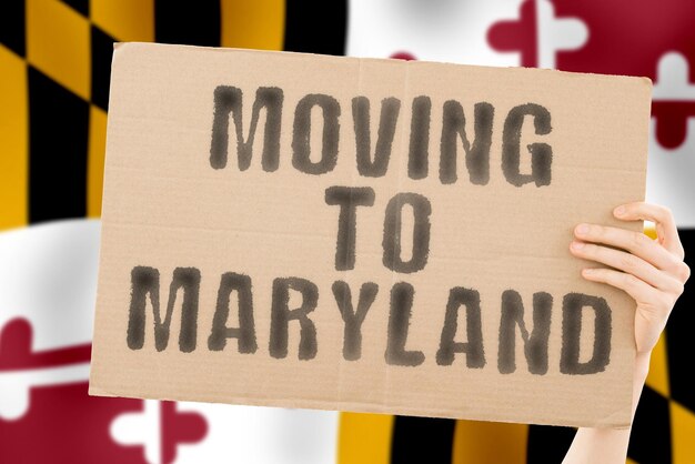 The phrase  Moving to Maryland  on a banner in mens hand with blurred sea on the background