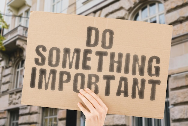 The phrase  Do something important  on a banner in mens hand with blurred background Huge