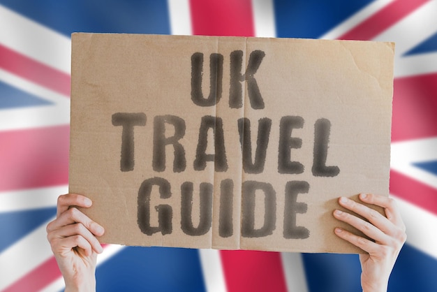 The phrase UK travel guide on a banner in mens hand with British flag Worldwide Terminal