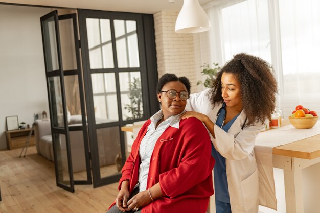 Physical therapy. Woman having course of physical therapy enjoying massage for shoulders by her nurse