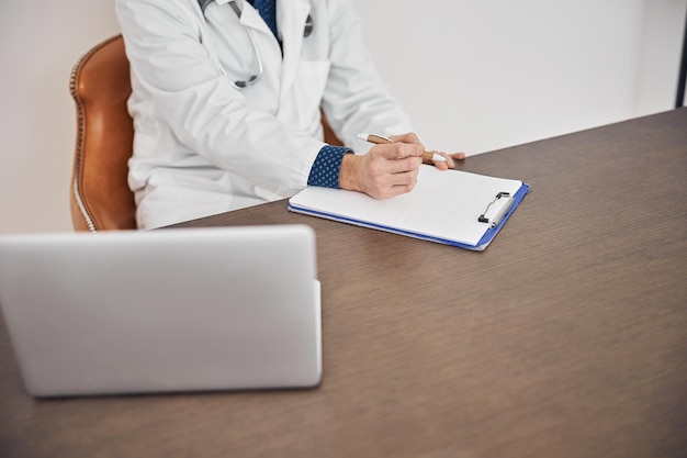 Physician with a pen in his hand sitting at the desk