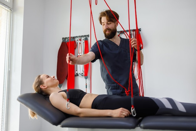 Physiotherapist assists female patient undergoing rehabilitative physiotherapy