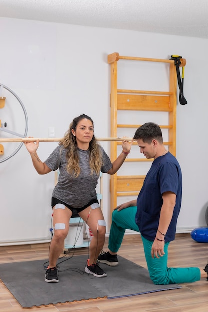 Physiotherapist correcting the exercises of a woman who is undergoing rehabilitation