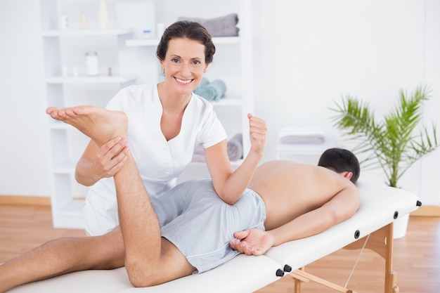 Physiotherapist doing leg massage and smiling at camera