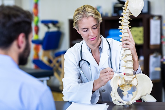 Physiotherapist explaining spine model to patient