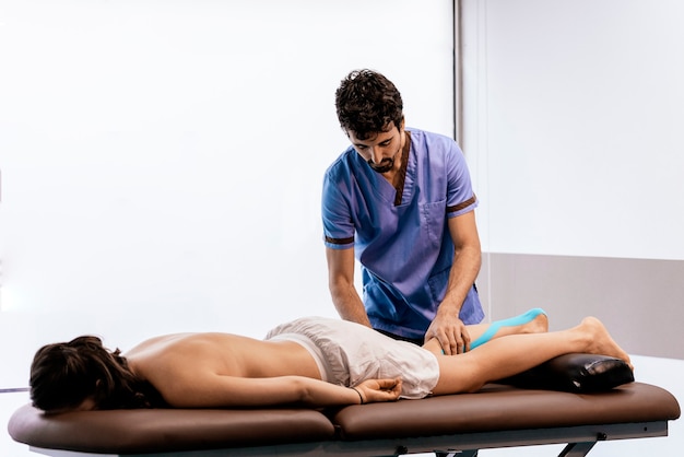 Physiotherapist giving calf therapy to a woman in clinic. Physical treatment concept