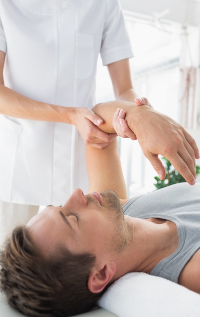 Physiotherapist giving hand massage to man