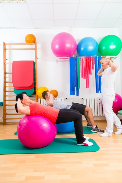 Physiotherapist giving patients gymnastic exercise