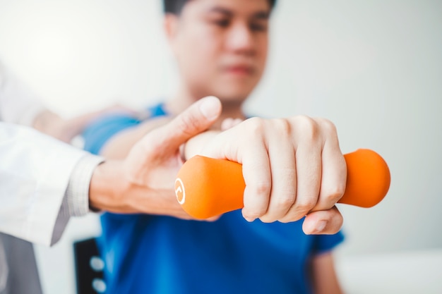 Physiotherapist man giving exercise with dumbbell treatment About Arm and Shoulder apy concept