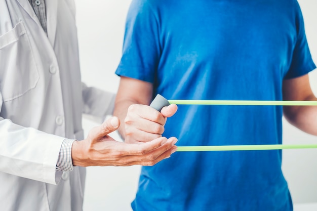 Physiotherapist man giving resistance band exercise treatment About Chest muscles and Shoulder of athlete male patient Physical therapy concept