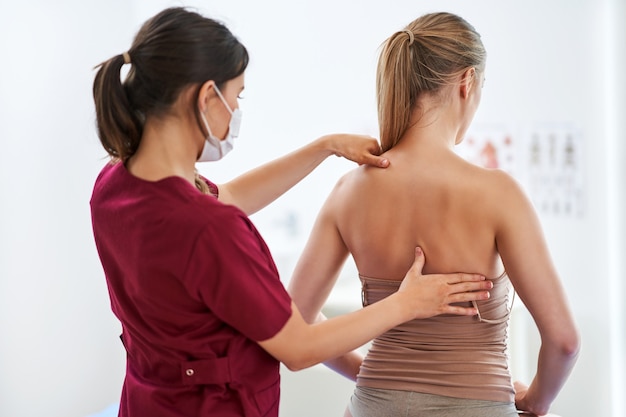 physiotherapist in mask helping female patient