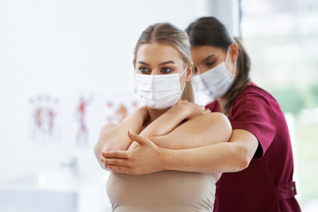 physiotherapist in mask helping female patient