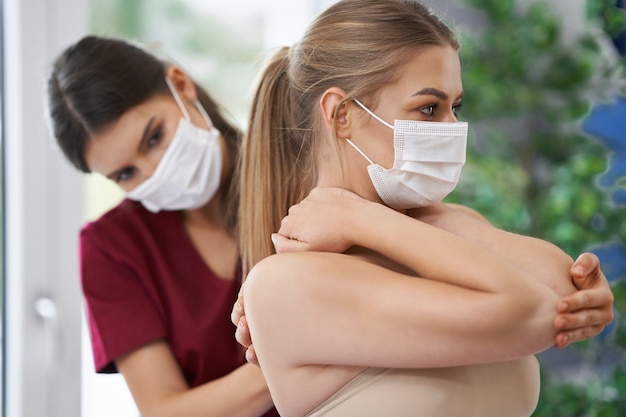 physiotherapist in mask helping female patient