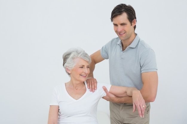 Physiotherapist massaging a smiling senior womans arm