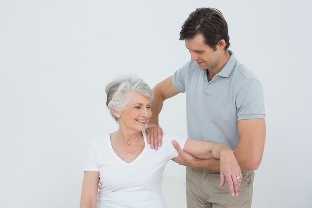 Physiotherapist massaging a smiling senior womans arm